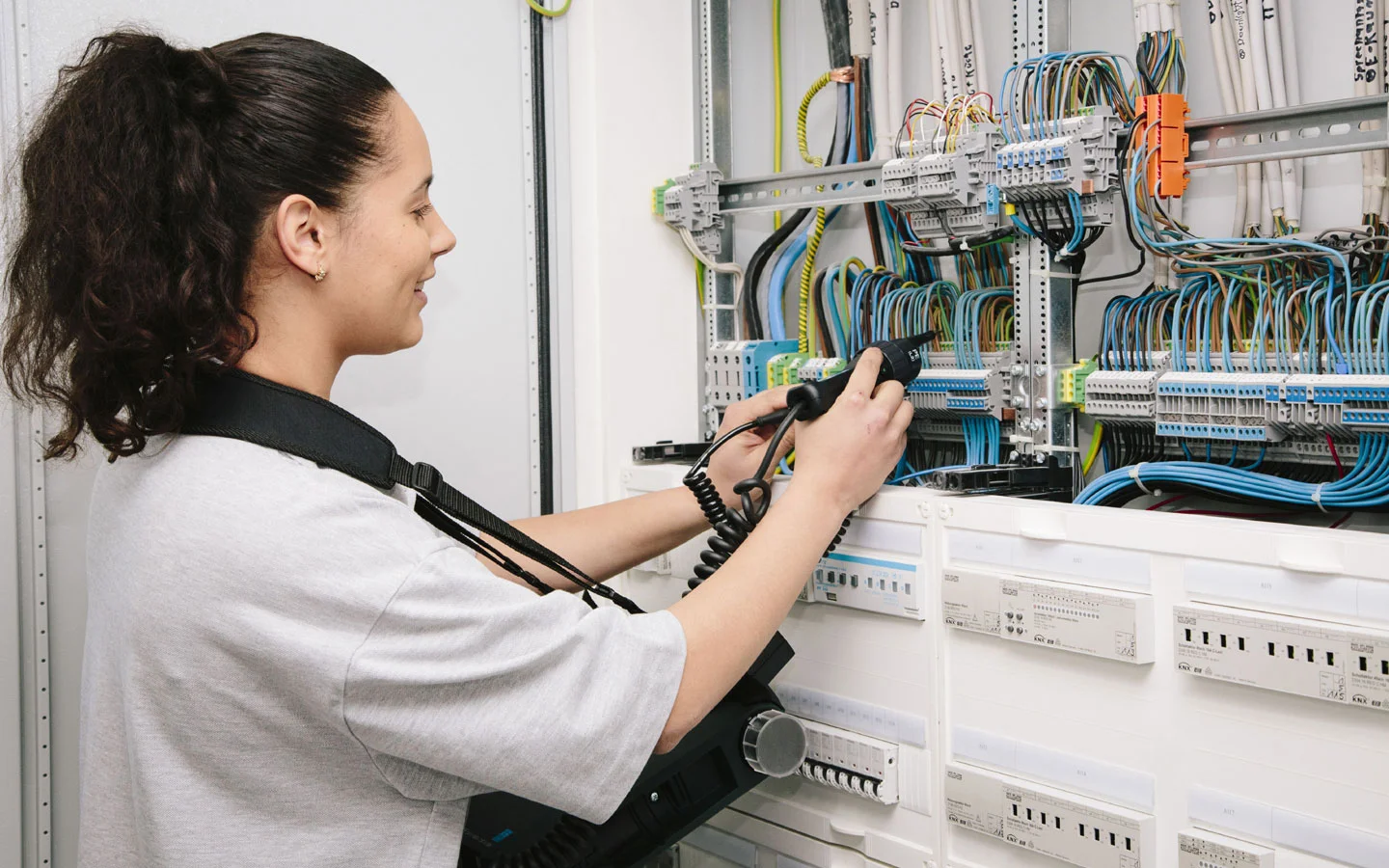E-CHECK - Mitarbeiterin prüft im Schaltschrank mit einem Meßgerät &middot; B+B Mess- und Sicherheitstechnik